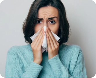 الصورة: امرأة مصابة بنزلة برد وتمسك منديلًا